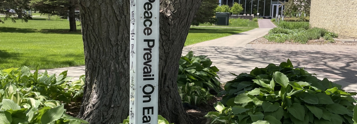 White pole that says "May peace prevail on Earth"